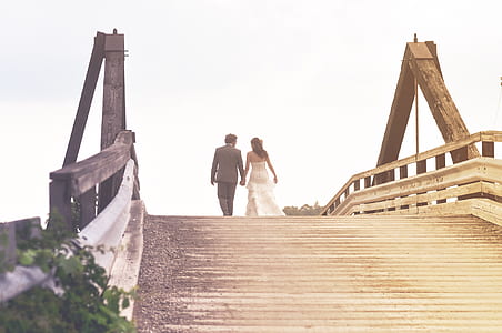 married couple walking on the footed bridge under white sky at daytime thumbnail