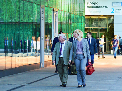 man and woman walking near building with glass walls thumbnail