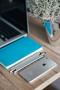 Silver iPhone with a blue notebook and pencils thumbnail