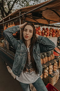 woman in blue denim jacket standing in front of fruit display thumbnail