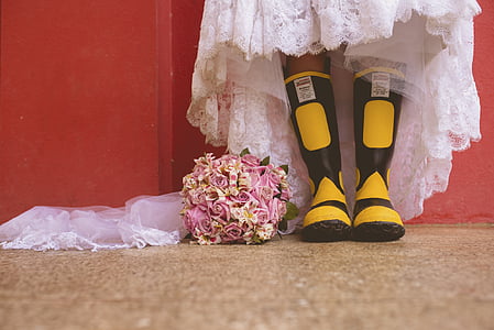 person wearing black-and-yellow rain boots beside flower bouquet thumbnail