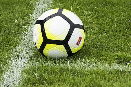white, black, and yellow soccer ball on green grass field thumbnail
