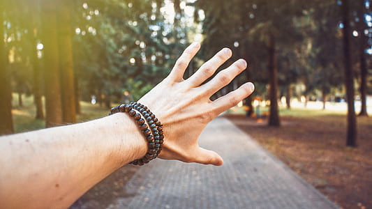 man widen his fingers in front of trees near pavements thumbnail