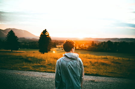 man wearing gray hooded jacket neat tree during sunset thumbnail