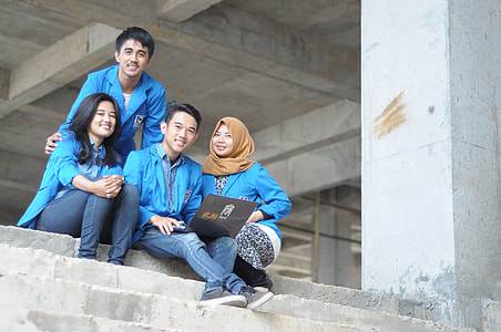 two men and two women wearing blue dress shirts sitting on gray concrete stair thumbnail