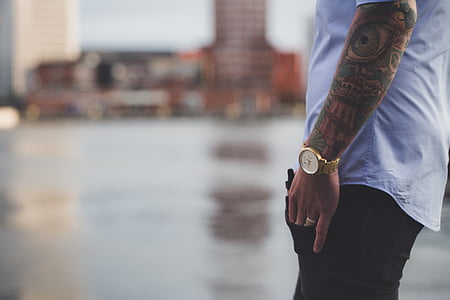 selective focus photography of man in white shirt, gold-colored analog watch, and black bottoms thumbnail