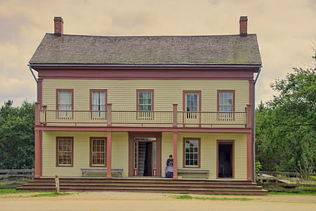 woman sitting outside yellow and pink painted 2-storey house thumbnail