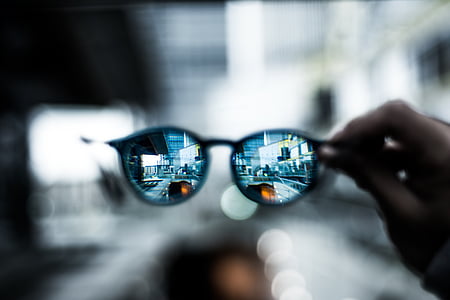 selective focus photography of person holding Clubmaster-style sunglasses thumbnail