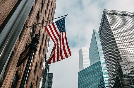 United State of America flag hanging gray metal stick near brown concrete building during daytime thumbnail