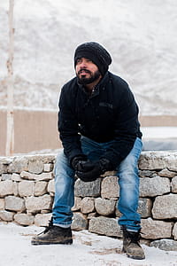 Man Sitting on Rock Wearing Black Jacket thumbnail