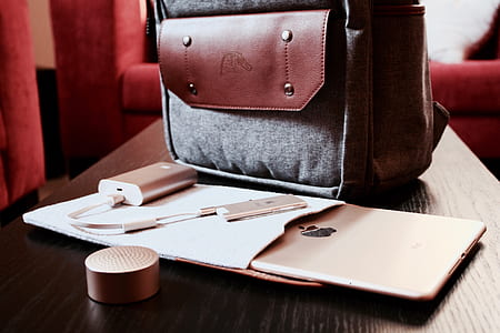 silver power bank beside bag and iPad on brown wooden table thumbnail