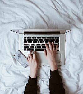 person hand on laptop beside smartphone thumbnail
