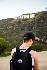 selective focus photo of person wearing black backpack standing infront of Hollywood sign during daytime thumbnail