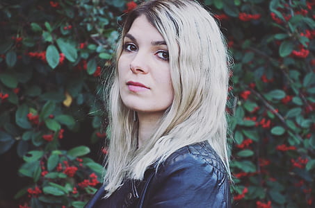 woman wearing black leather top next to red petaled flower thumbnail