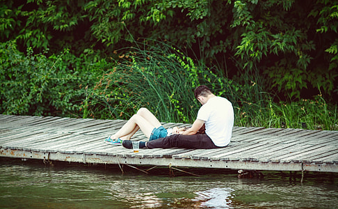 couple sitting and laying on dock during day time thumbnail