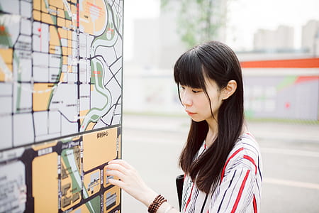 woman touching map board during daytime thumbnail