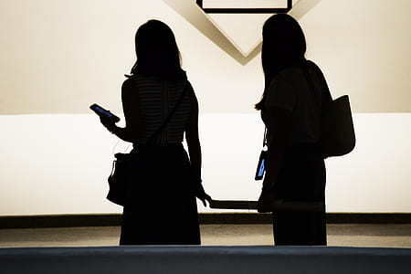 silhouette of two women holding smartphone thumbnail