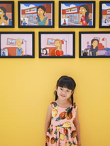 girl standing behind the wall with assorted cartoon photos thumbnail