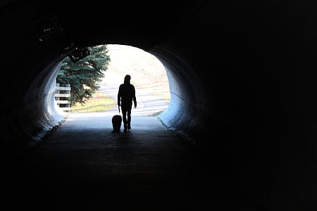 silhouette of person walking inside tunnel at daytime thumbnail