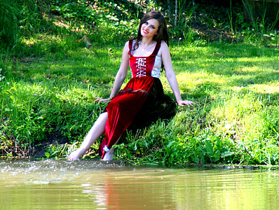 woman sitting on grass in front of body of water thumbnail