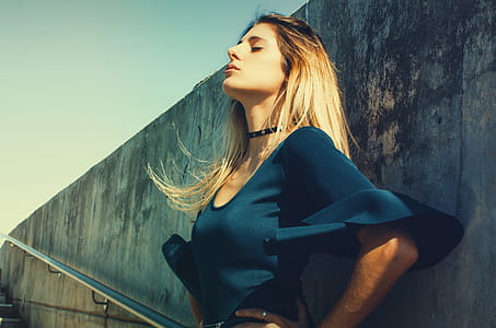 Woman Wearing Blue Scoop-neck Top Standing Near Gray Concrete Wall thumbnail