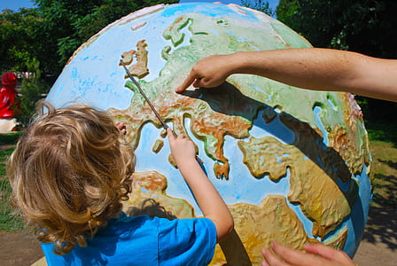 boy wearing blue t-shirt learning globe during daytime thumbnail