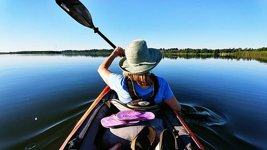 woman sitting on red kayak near green trees during daytime thumbnail