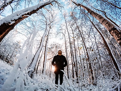 man standing on snow-covered forest during daytime thumbnail