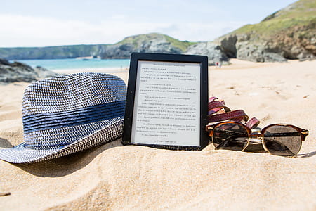 Shallowfocus Photography of Fedora Hat, Photo Frame, and Sunglasses on Beach thumbnail