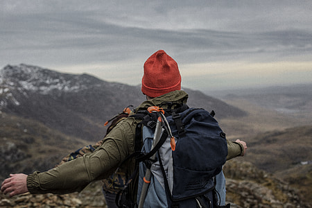 man standing on mountain while spreading his arms thumbnail