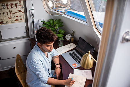 man writing on paper while sitting on chair during daytime thumbnail
