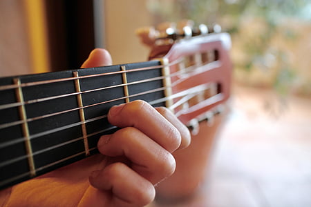 person holding brown classical guitar thumbnail