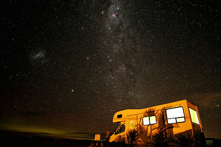 brown recreational vehicle parked near plants during nighttime thumbnail