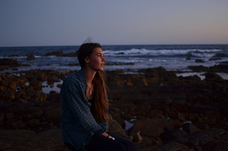 woman wearing blue dress shirt sitting on seashore during daytime thumbnail