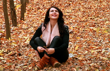 woman in black long-sleeved top and black pants sitting on brown leaves thumbnail