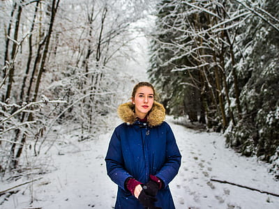 woman n blue parka jacket surrounded by snow-covered trees thumbnail
