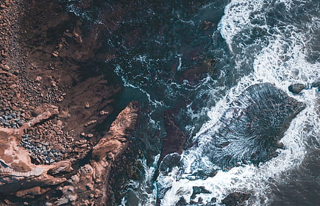 aerial photography of body of river beside brown rock thumbnail