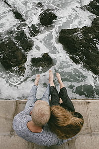 couple sitting on ocean creek watching ocean waves during daytime thumbnail