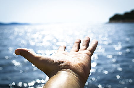 person's hand reaching the ocean thumbnail