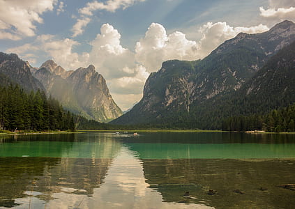 green tree covered mountain near lake under white cloudy sky thumbnail