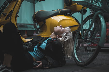 Photography of Woman Laying on Ground Near Scooter thumbnail