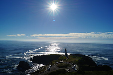 lighthouse on island beside body of water during daytime thumbnail