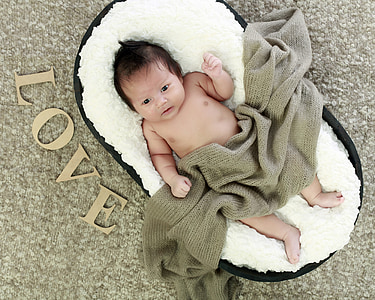 baby lying on co-sleeper with gray blanket thumbnail