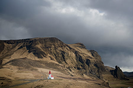 red and white chapel near brown plateau photo during cloudy day thumbnail