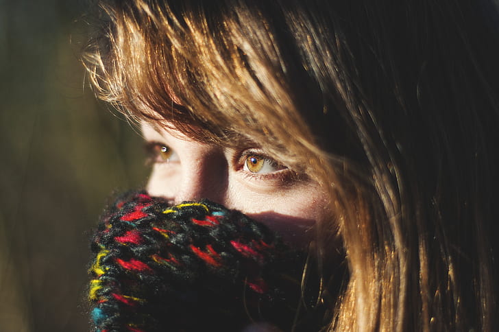 woman covering face with knit textile in tilt shift photography