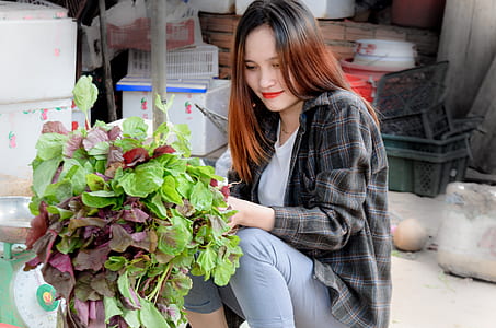 woman sitting beside green and purple plants thumbnail