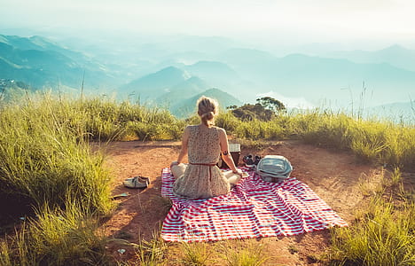 woman sitting on multicolored textile looking on mountains during daytime thumbnail