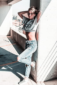 woman in gray crop top raising both hands while leaning on gray concrete wall during daytime thumbnail