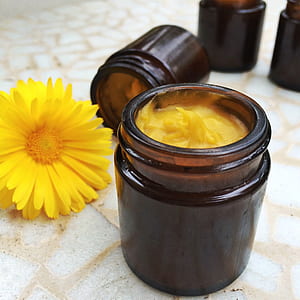 yellow cream inside amber tinted bottle near yellow daisy thumbnail