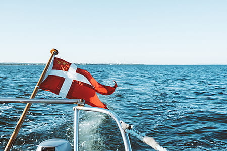 boat with red and white flag with cross under during daytime thumbnail